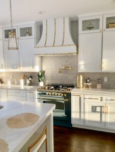 natural light filtering into kitchen with a white Hoodsly Curved hood with brass strapping and buttons