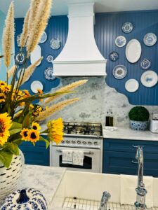 blue and white kitchen with antique plate wall featuring a white Hoodsly Curved hood