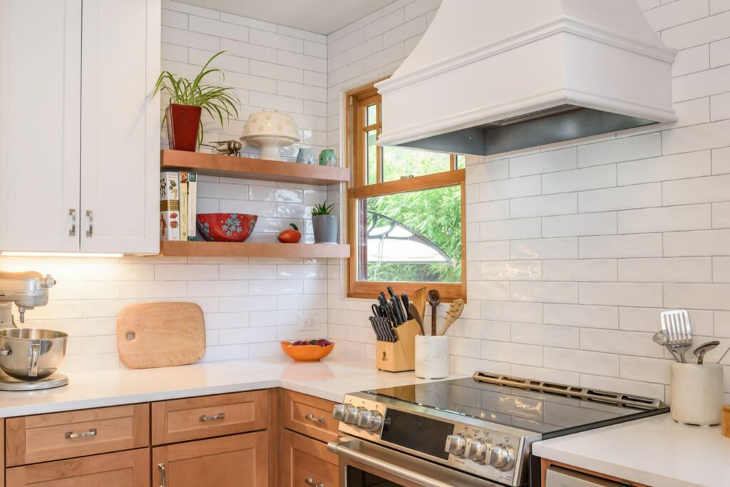 white and light wood kitchen featuring Hoodsly raw floating shelves and white curved range hood with classic trim